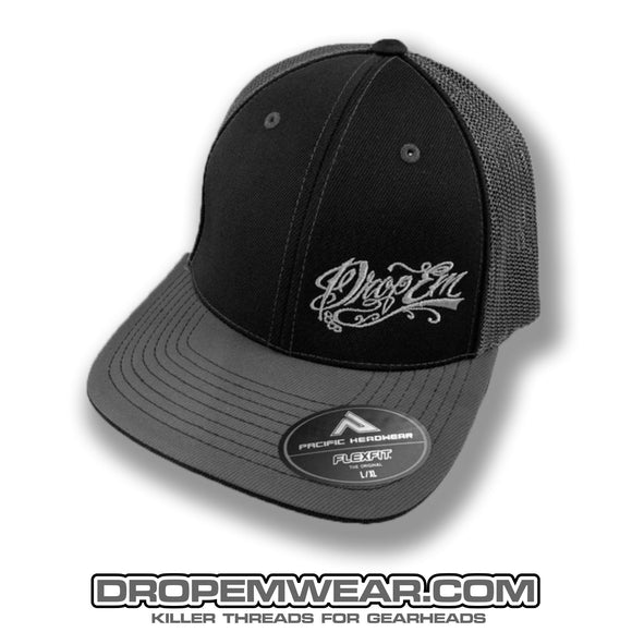 PACIFIC HEADWEAR CURVED BILL FITTED TRUCKER HAT BLACK/GRAPHITE WITH TATTOO SCRIPT LOGO ON LEFT PANEL