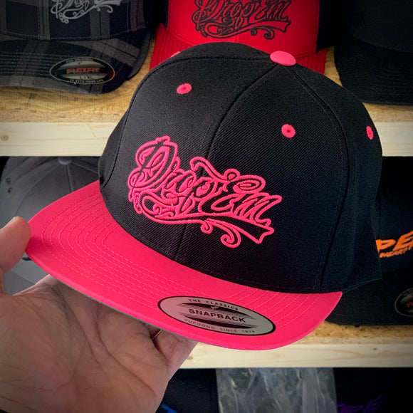 BLACK FLAT BILL SNAP BACK WITH NEON PINK BILL AND NEON PINK TATTOO SCRIPT LOGO